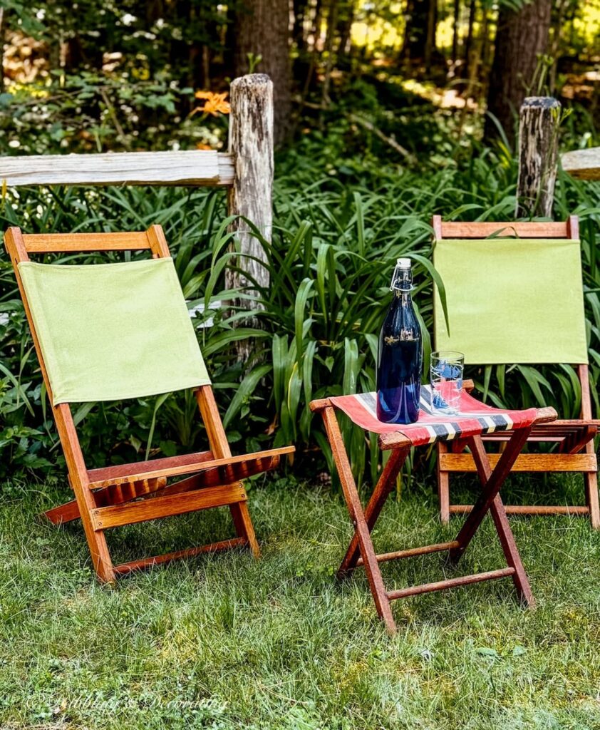 Two thrifted retro camp chairs with stool in garden set up during the summer.