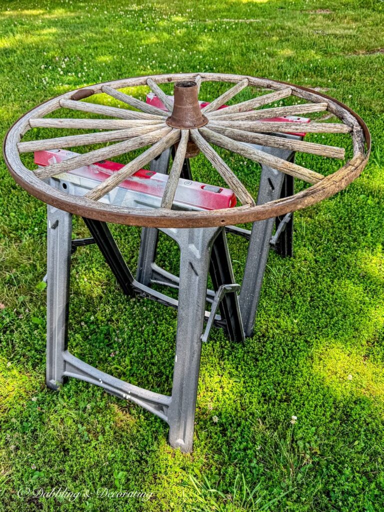 Weathered old wagon wheel on painting horses before painting.
