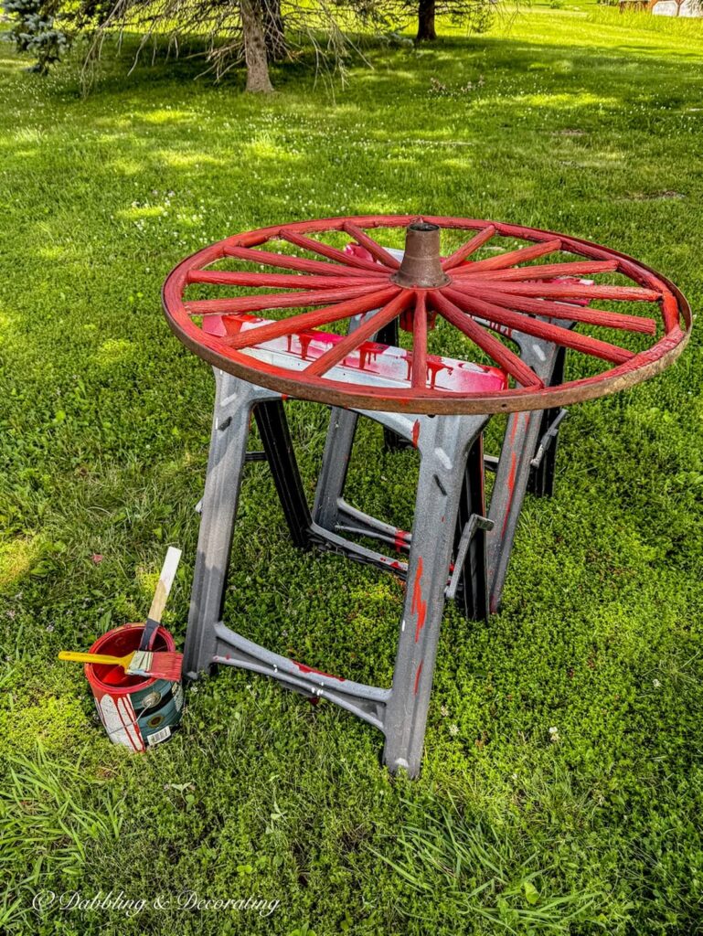 Old wagon wheel just painted red on horses on lawn set to dry.
