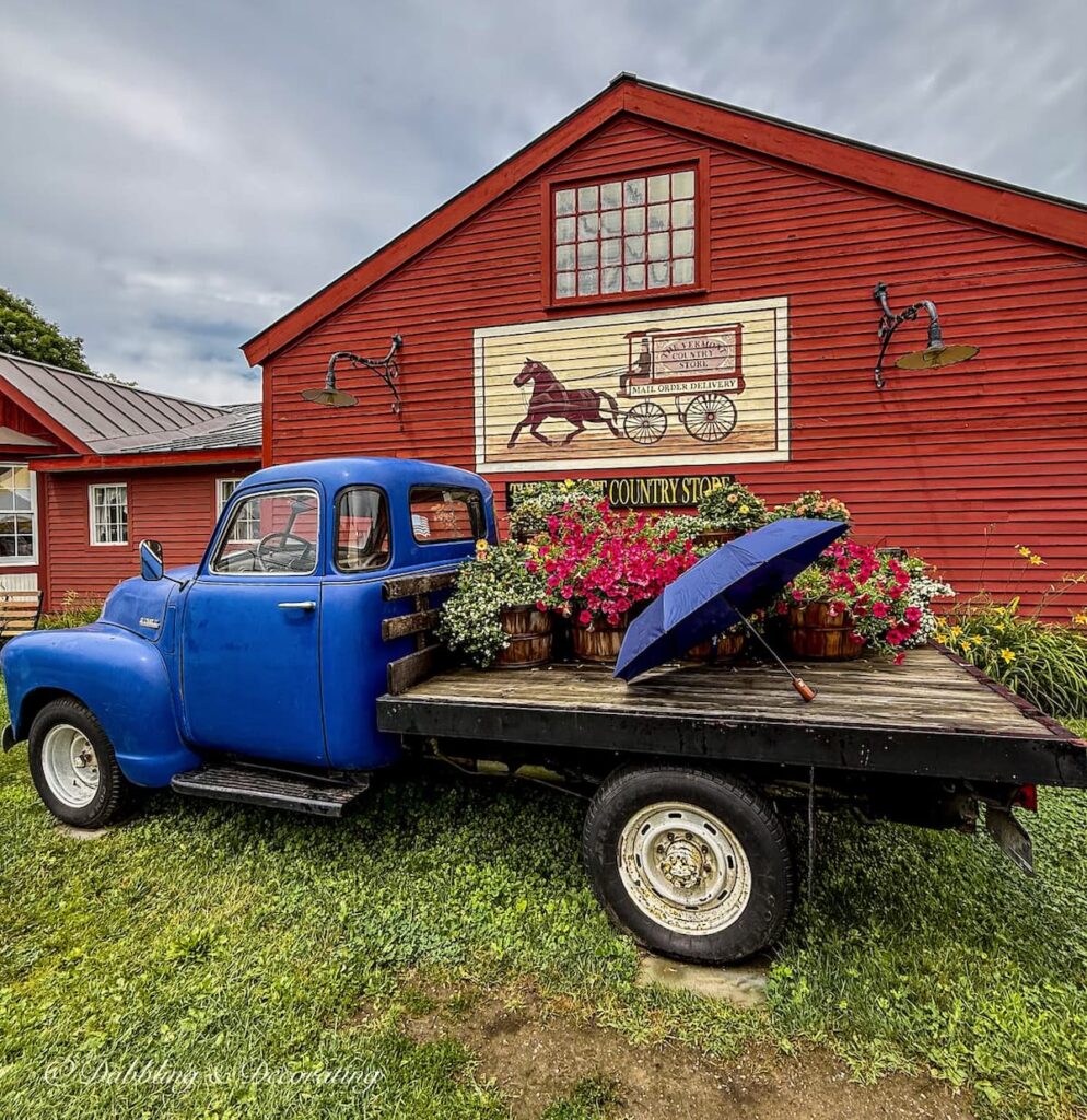 The Vermont Country Store where you'll find Old-Fashioned Household Favorites. Old Blue truck with flowers, and umbrella on a rainy Vermont day. 