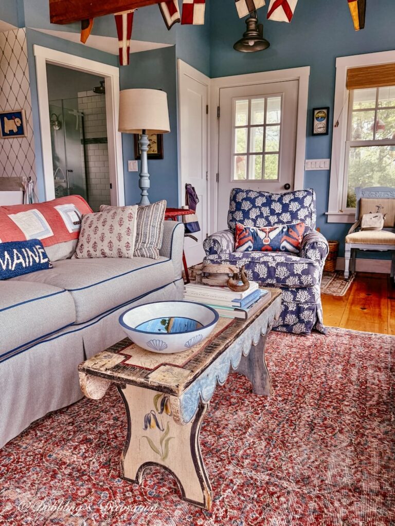Inside a coastal guest cottage in Maine with a vintage red rug grounding the living room area floors.