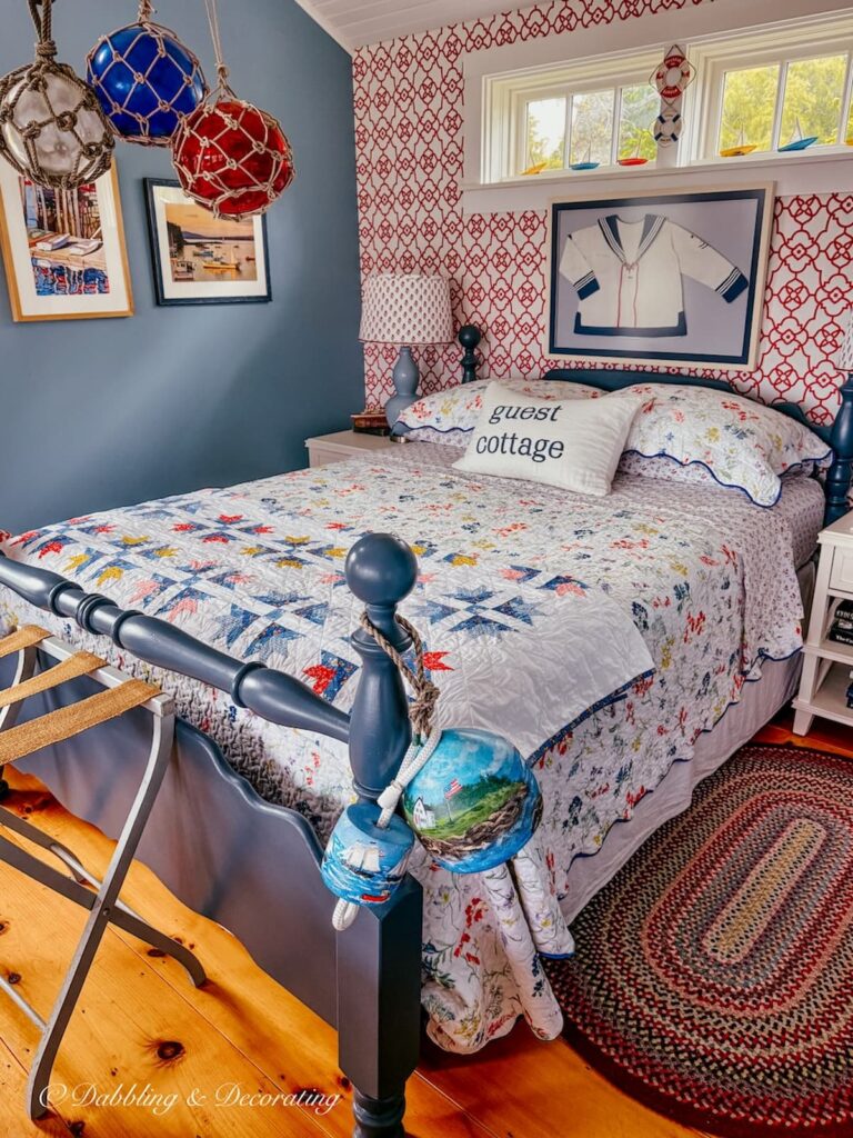 Bedroom in coastal guest cottage with nautical details like lobster buoys draped around a bed post.