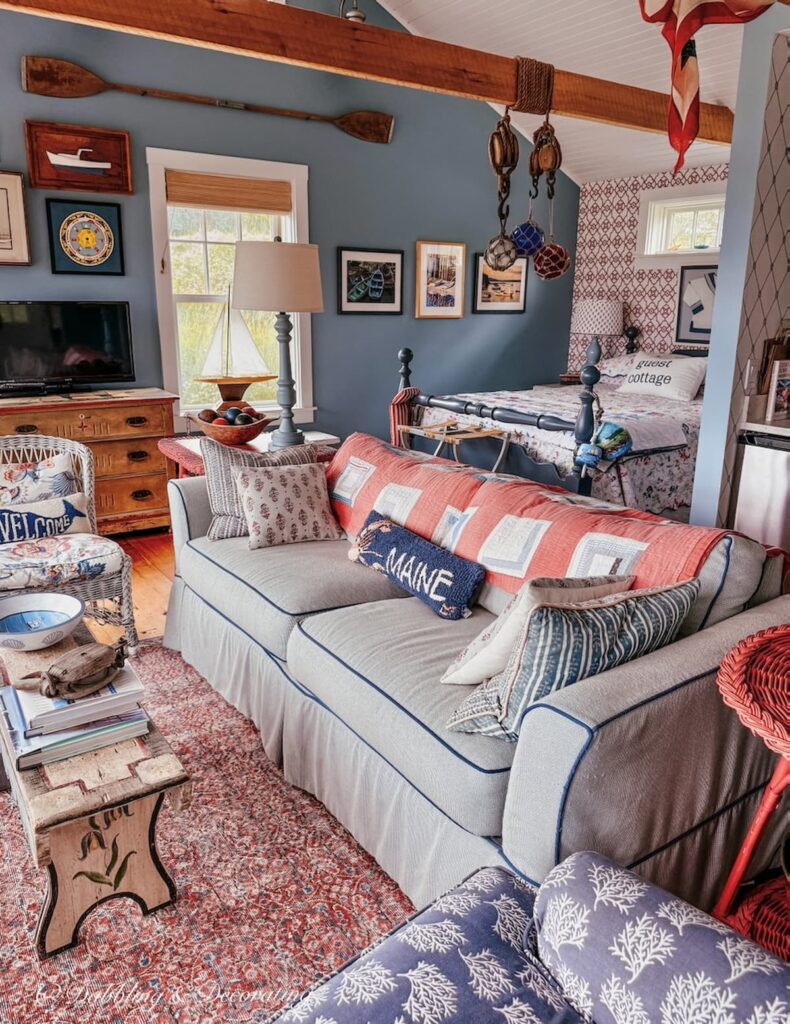 Inside a colorful and vintage styled guest cottage on the coast of Maine. Living room, bedroom, and kitchen combined in a small open space.