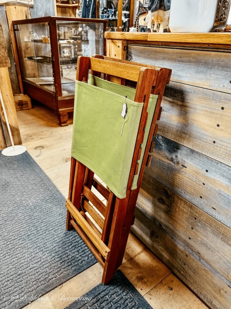 Two retro teak camping chairs leaning up against the antique store counter.