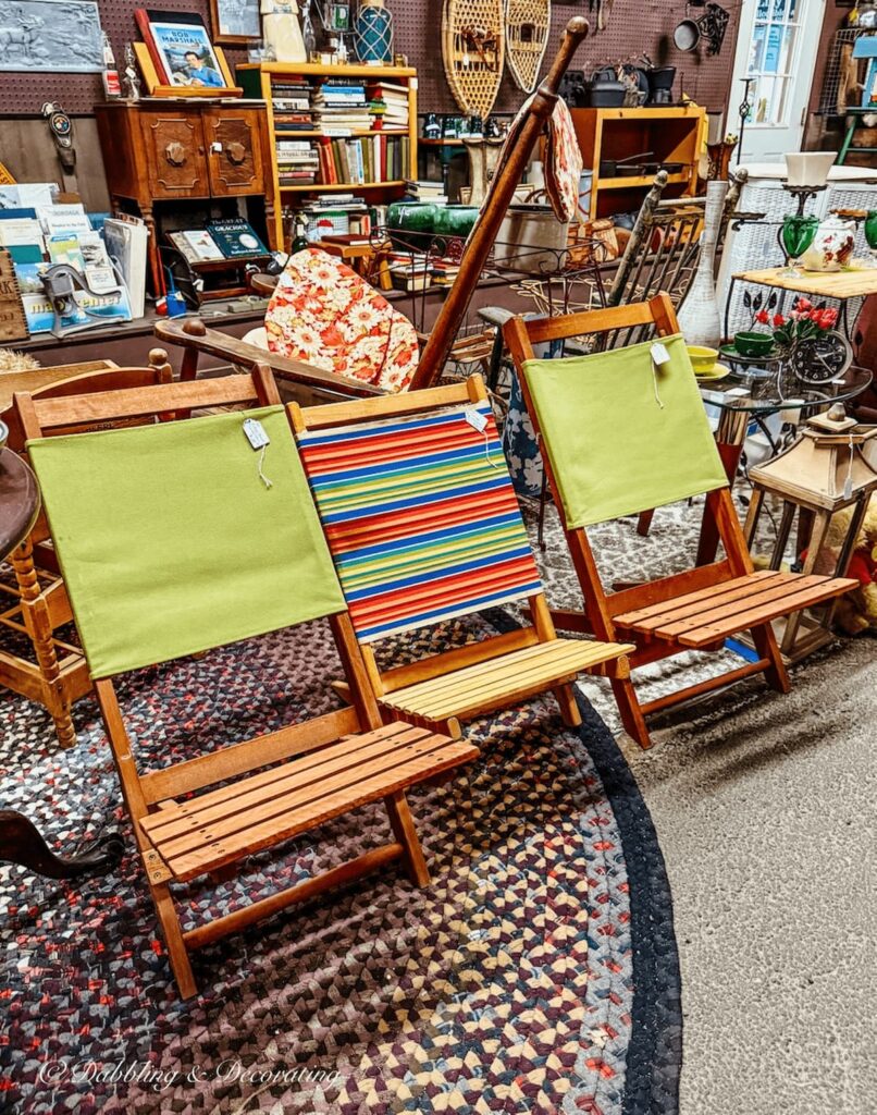 Three vintage teak camping chairs with colorful fabric at Hay Fields Antique store.