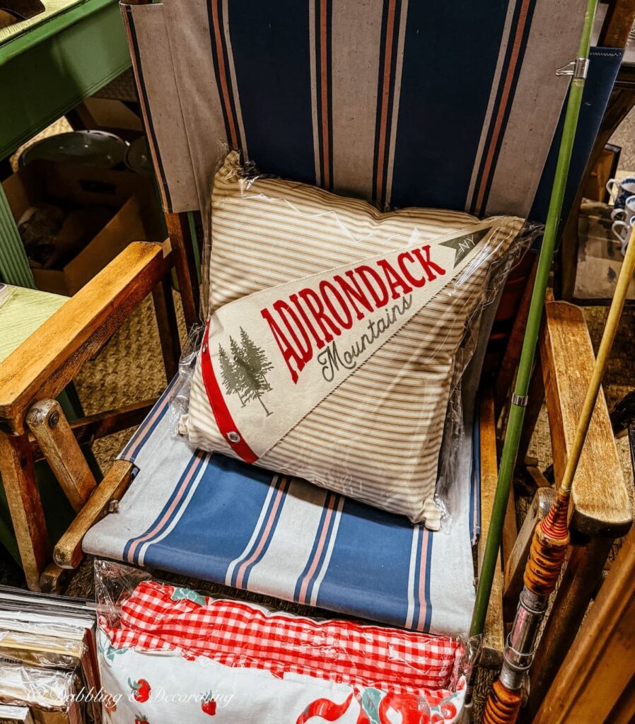 Handmade Adirondack pillow with Adirondack banner sewed on it on camping chair in antique store.