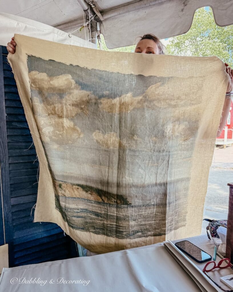 Coastal inspired vintage tapestry in vintage booth vendor's hand showing it off.