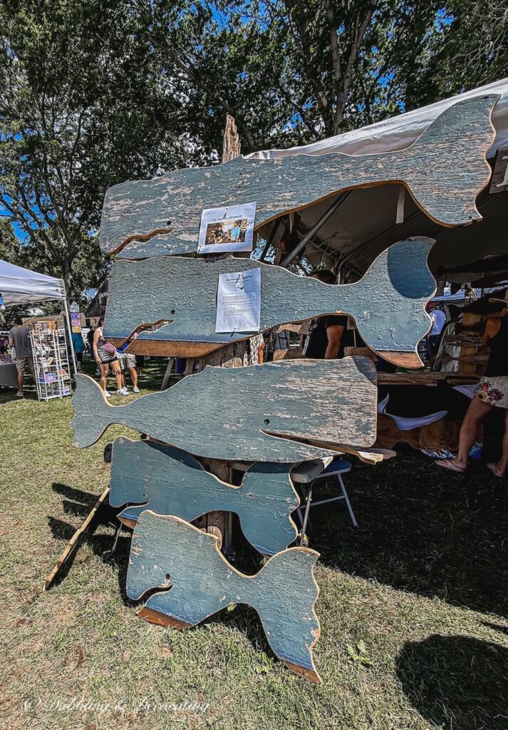 Vintage barn wood handmade whales with a beautiful rustic blue hanging in an antique booth at Vintage Bazaar New England.