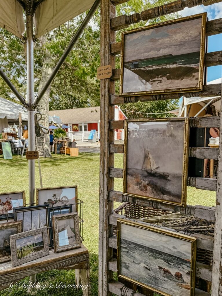 Coastal Paintings on tent antique booth display framed with brass frames at Vintage Bazaar New England.