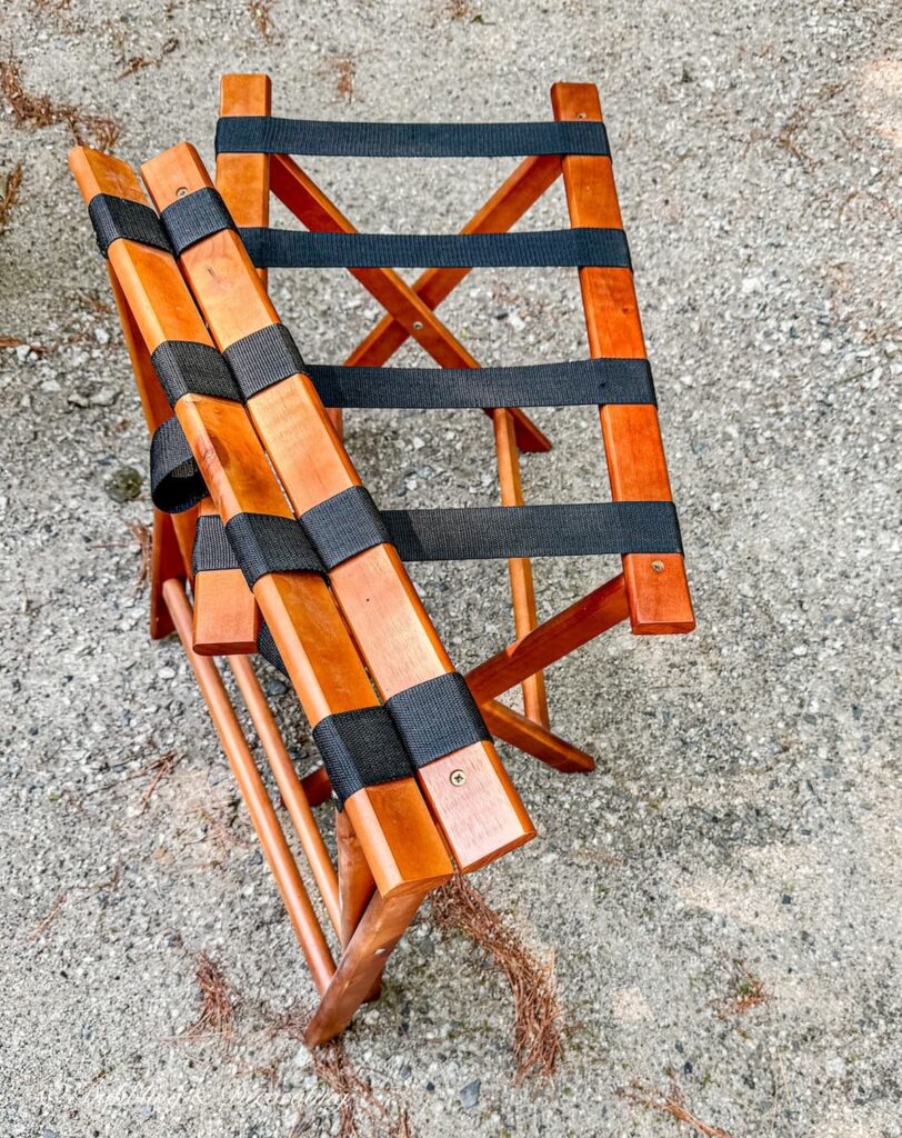 Two laminate orange folding luggage racks with black webbing in driveway.