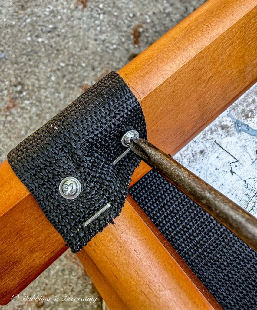Phillips screwdriver removing screws from the bottom of a folding luggage rack makeover