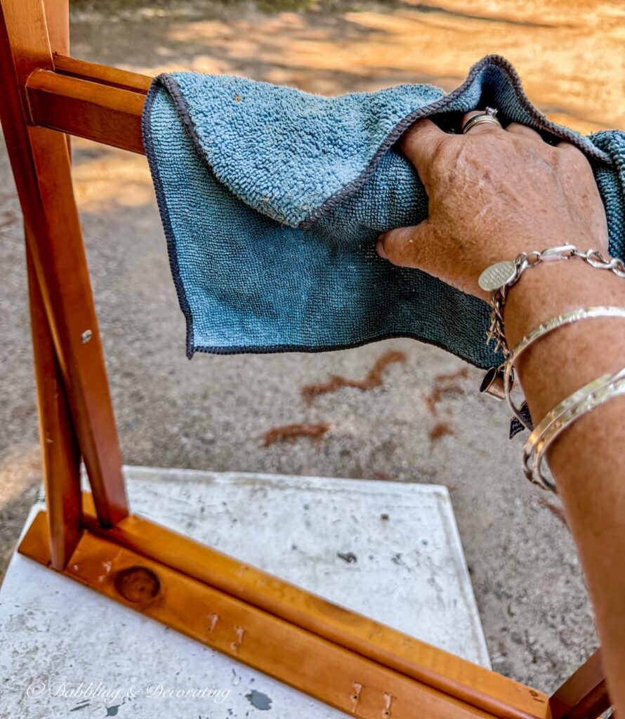 Wooden folding luggage rug getting a rub down with a blue rag before a DIY makeover.