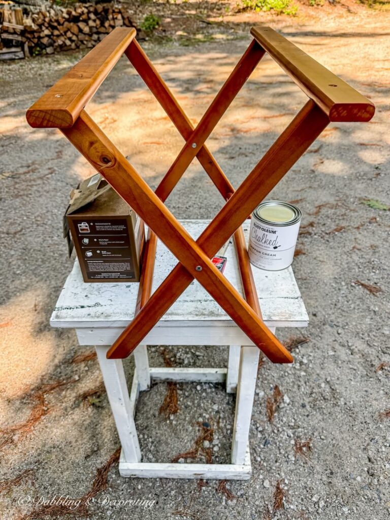 Wooden luggage rack secured on top of white table in driveway ready for painting.