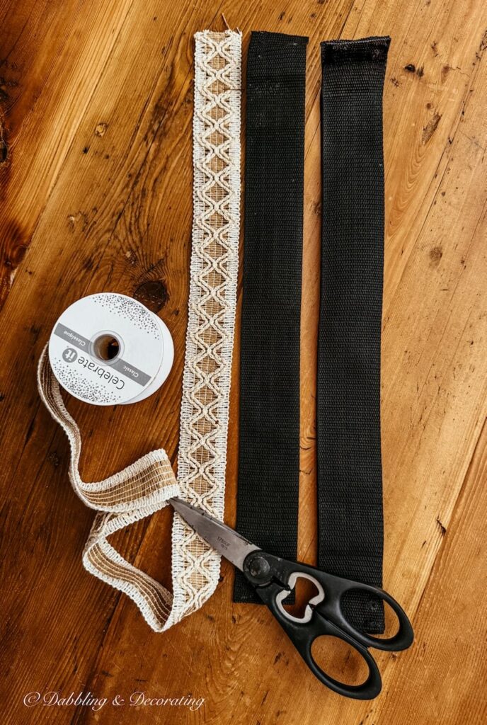 Two old black webbing from a luggage rack next to new ribbon ready to be measured and cut.