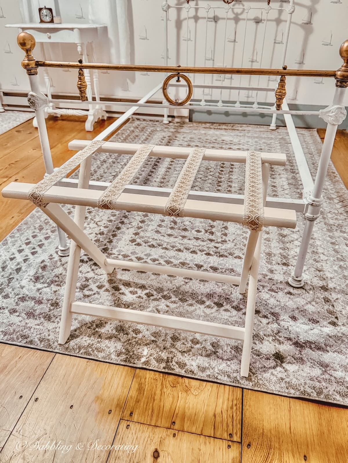DIY folding luggage rack makeover in guest bedroom with new antique wrought iron white bed and rug in attic.