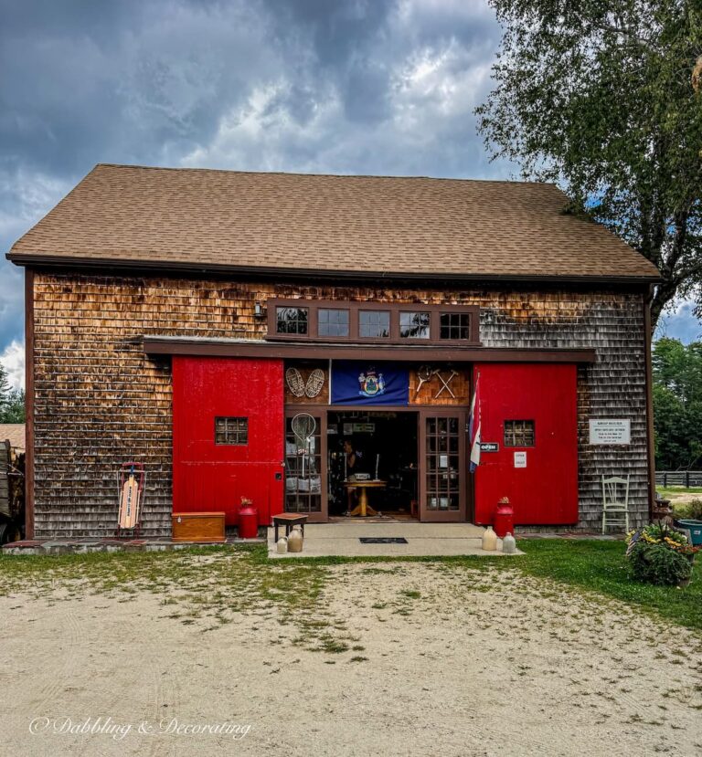 Antique Barn and store in mid coast Maine with open red doors and cedar shake siding with antiques displayed.