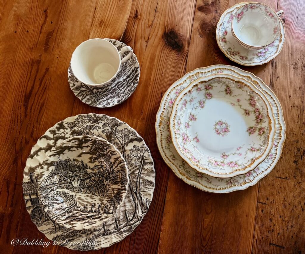One brown and white transferware place setting next to a Theadore Haviland Limoge pink and white place setting family heirlooms on wooden antique table.