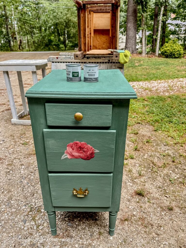 Painted green bedroom side table with rose transfer outdoors after Annie Sloan Wax applied.