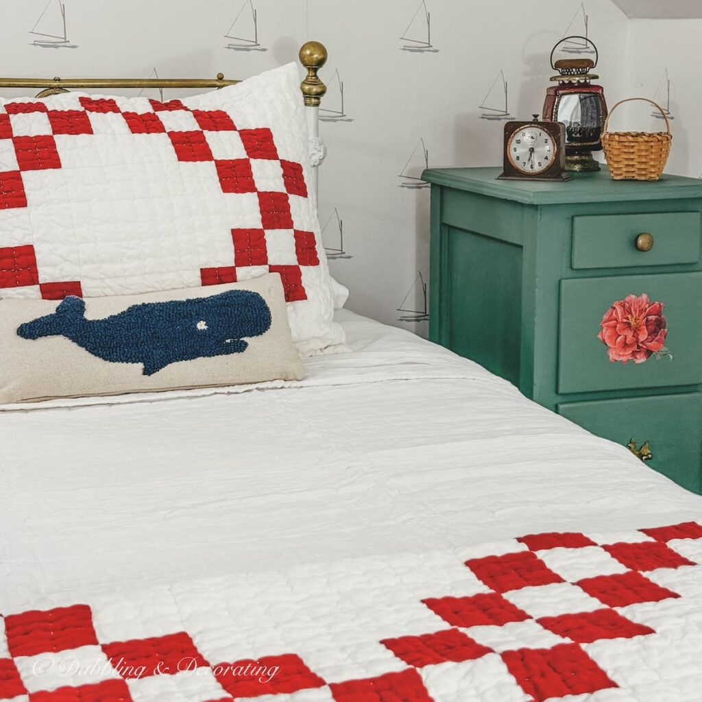 DIY painted green nightstand next to small guest room attic twin antique wrought iron bed with red and white bedding and whale pillow.