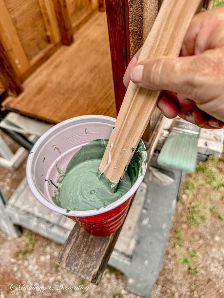 The mixed color of Annie Sloan's Amsterdam Green and Country Grey with paint stick in plastic container.