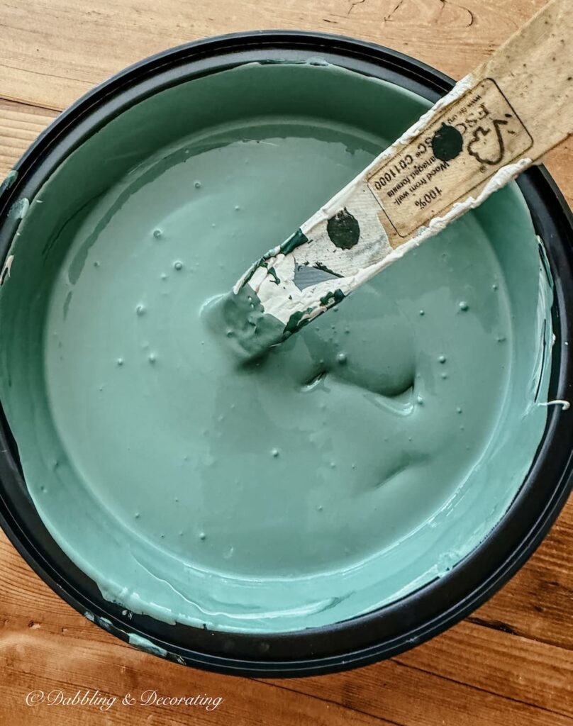 The mixed color of Annie Sloan's Amsterdam Green and Country Grey with paint stick in plastic container.