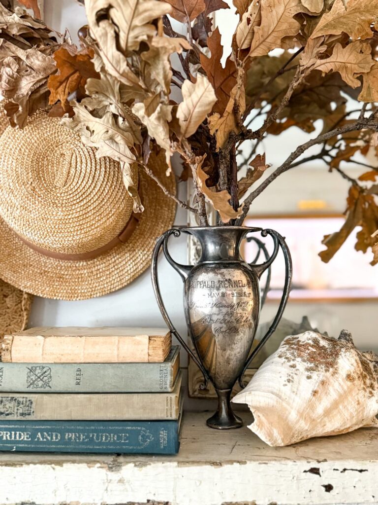 Coastal Grandmother Fall decorating ideas with straw hat and foraged brown leaves.