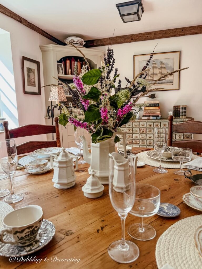 Antique styled dining room with wooden round table styled for fall surrounded by Benjamin Moore's Simply white plaster walls.