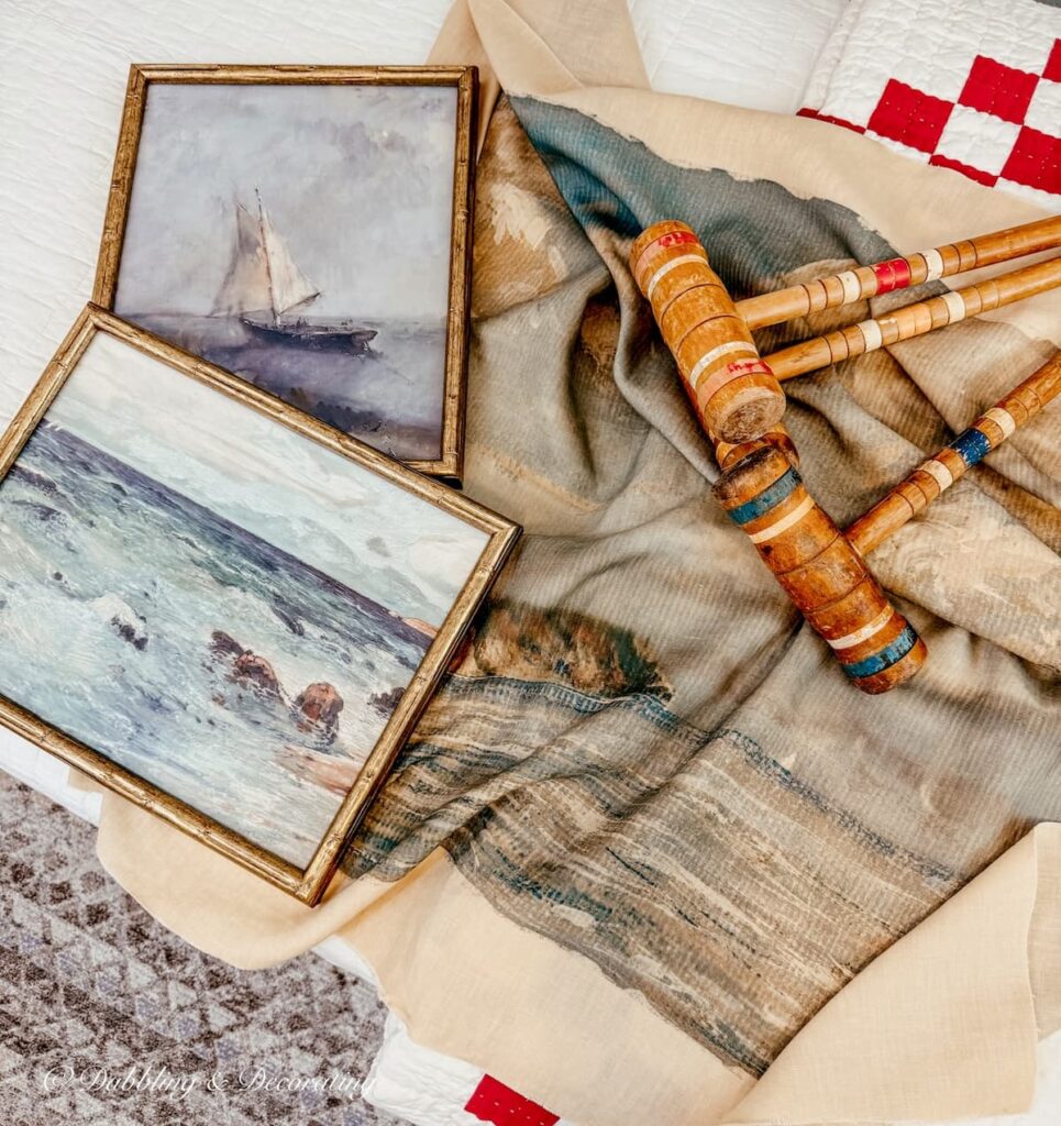 Thrifted Bedroom Ideas with old croquet mallets, coastal tapestry and seaside paintings on bed.