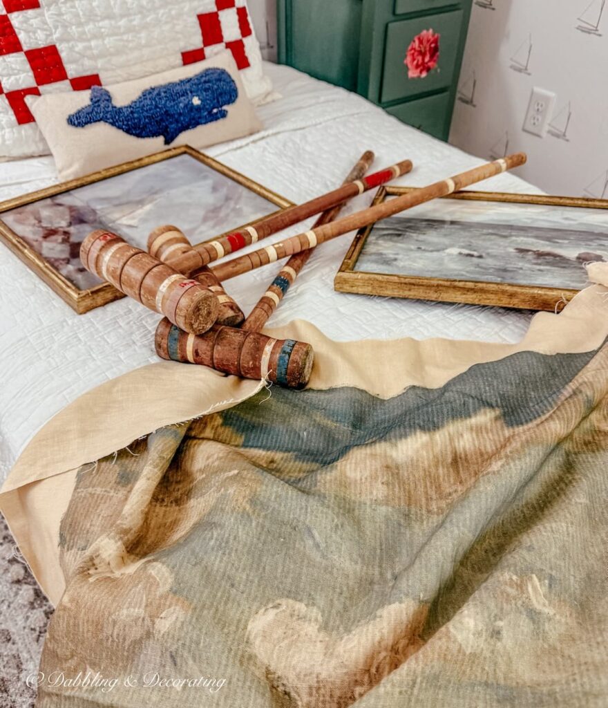 Thrifted Bedroom Ideas with old croquet mallets, coastal tapestry and seaside paintings on bed.
