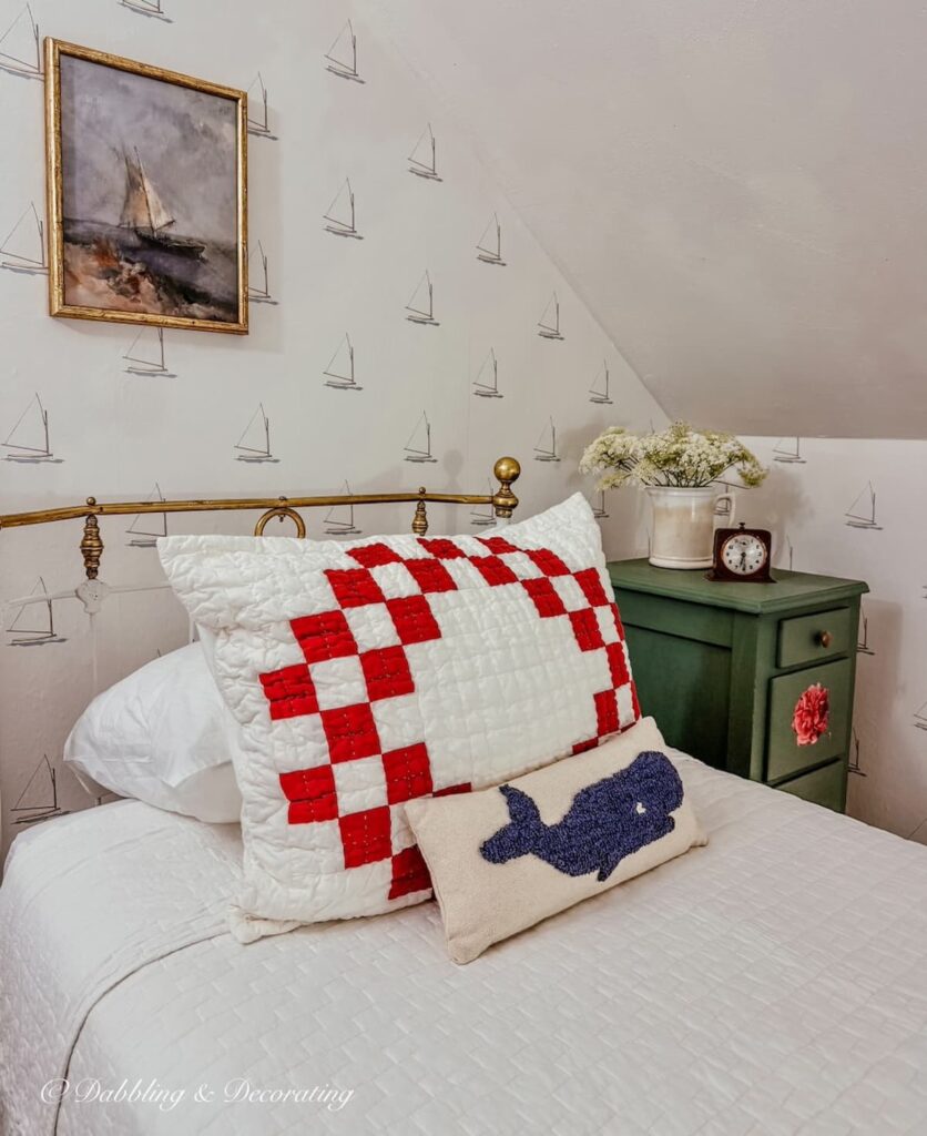 Thrifted bedroom ideas with a coastal sailboat print, red check pillow, whale pillow and DIY nightstand and an antique bed.