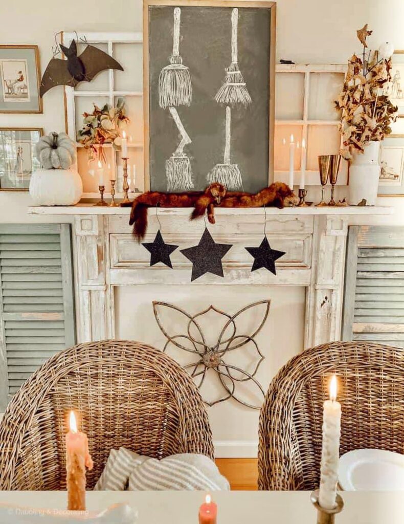 Vintage Halloween ideas: styled dining room mantel with vintage chalkboard with sketched with brooms, old black stars, bats, brass candlesticks, and more.