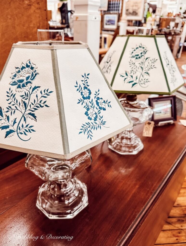 Two vintage oil lamps with lamp shades converted to electric lamps at antique store.