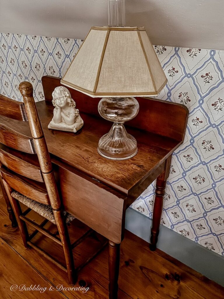 Antique wooden table with chair in bedroom styled with vintage oil lamp with lamp shade unwired and head bust.