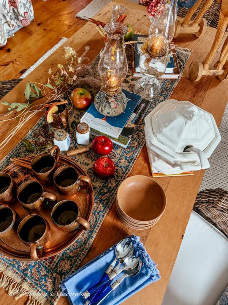 Fall table set with vintage copper, wooden bowls, antique oil lamps, old spice jars, vintage soup tureen and foraged branches for an autumn gathering.