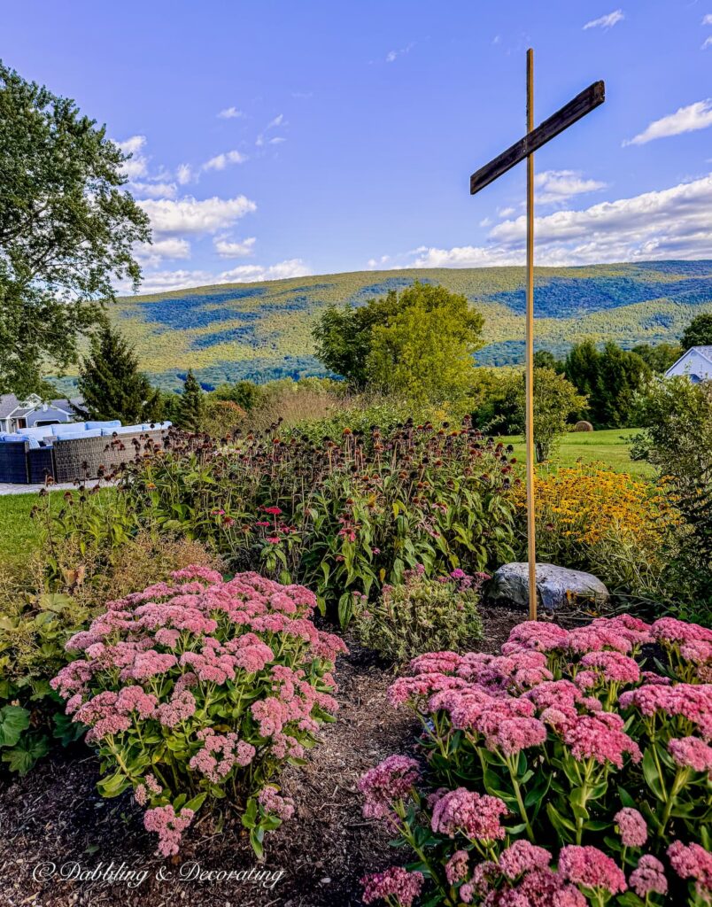 A wooden cross in a flower bed in the mountains; the base of our fall scarecrow in Vermont.