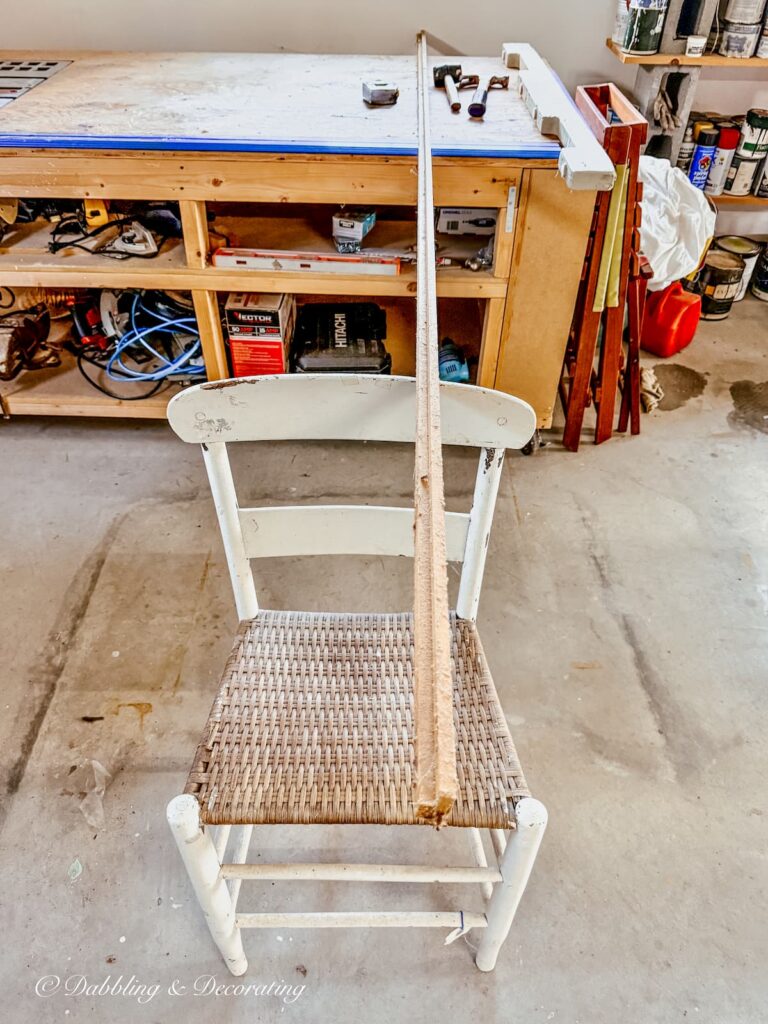 8 foot long wooden trim board in workshop resting on a chair for a fall scarecrow foundation.