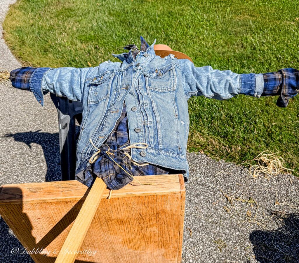 Fall scarecrow getting stuffed with straw and dressed with thrifted denim on saw horses in driveway.
