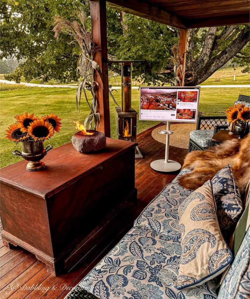 Colorful Fall Porch in Vermont with sunflower bouquets, table top fire, Timber Pellet Heater, and portable television with all weathered wicker furniture and custom slipcovers.