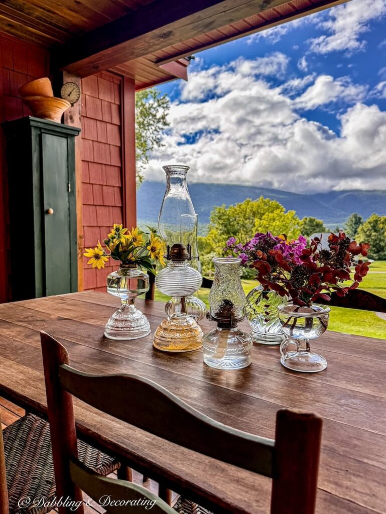 Antique oil lamps gathered on an outdoor colorful fall porch table in the mountains of Vermont.