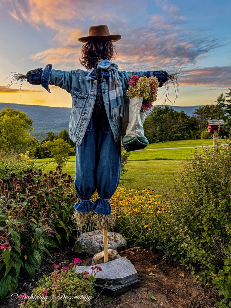 Moxie Mae our fall scarecrow in the mountains layered with thrifted blues and a bag of fall hydrangeas on her arm.