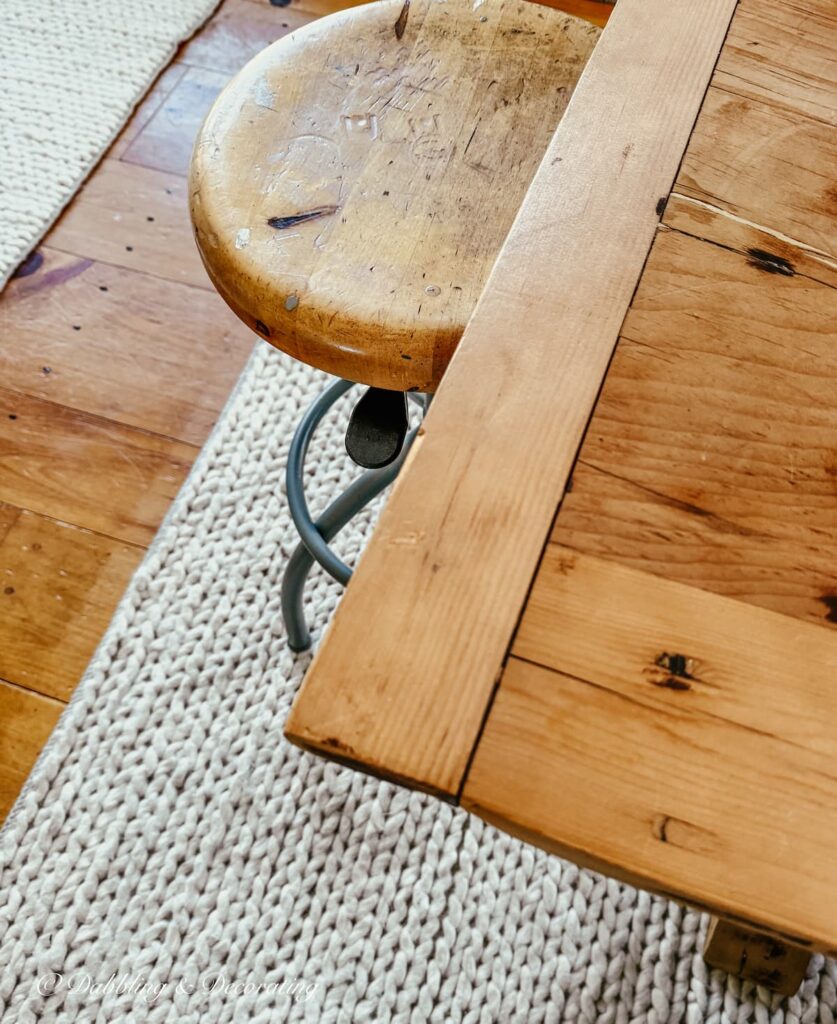 Vintage drafting stool underneath a wooden table close up after restoration.