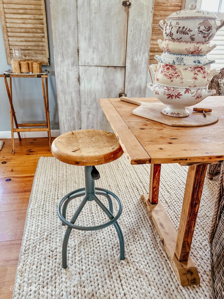 Vintage drafting stool restored with blue-gray paint color in room off kitchen with large table and antiques.