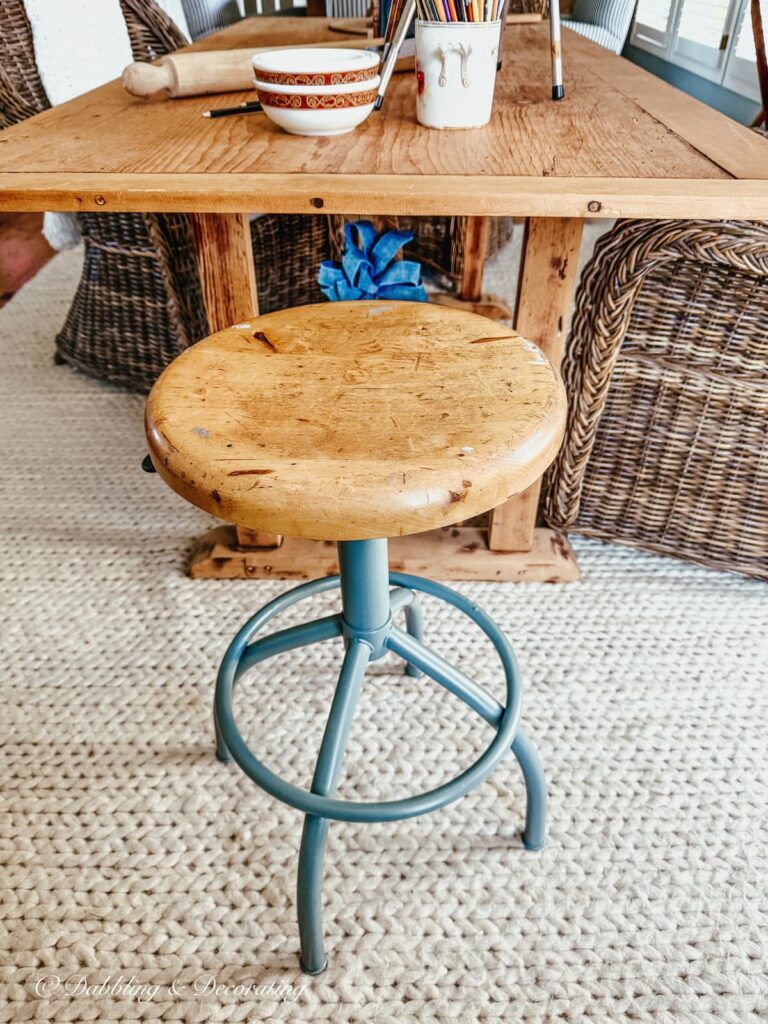 Rusty antique drafting stool restored with blue-tray paint in vintage-styled kitchen scullery.
