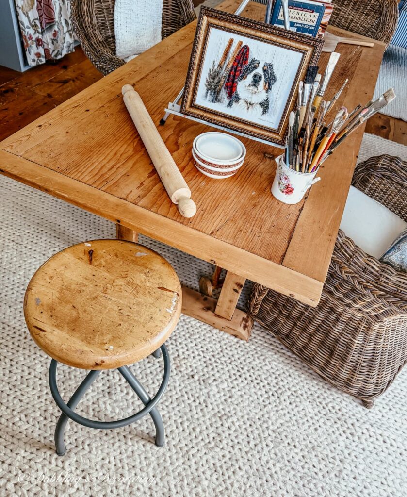 Rusty antique stool restoration now in blue-gray on white rug under wooden table in kitchen scullery.