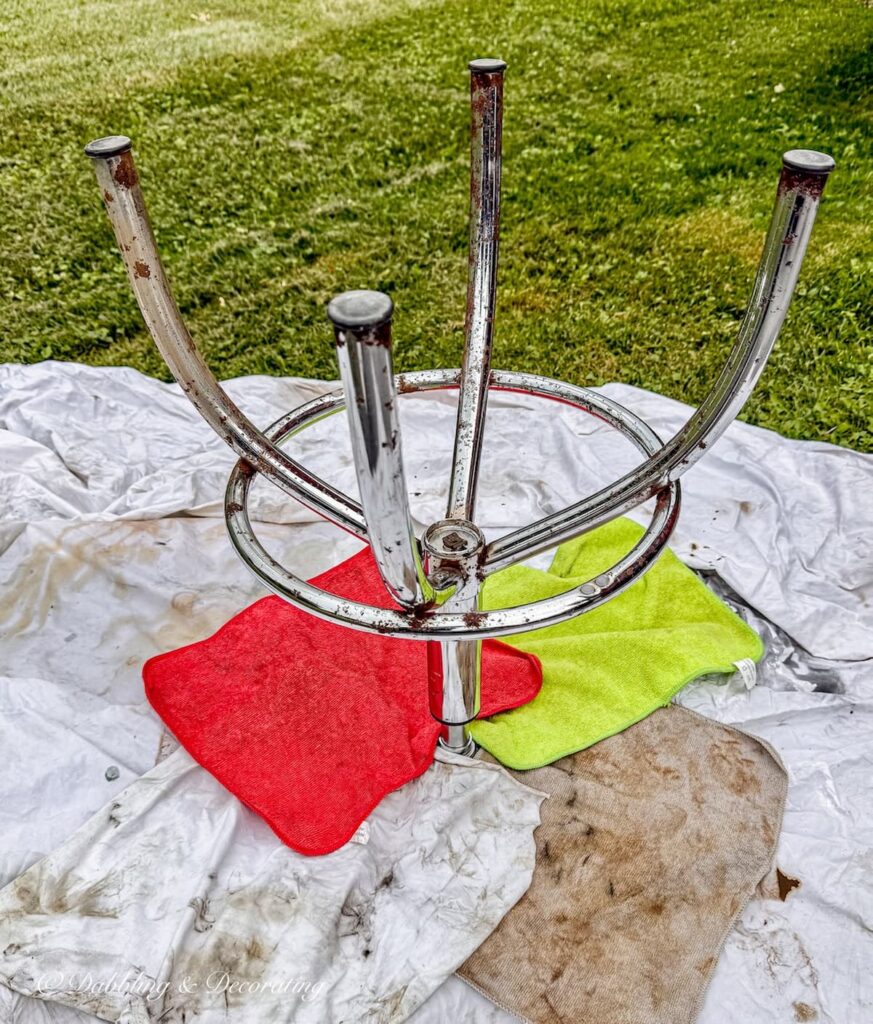 Upside down drafting stool with metal legs ready to prime and wooden stool top covered in rags.