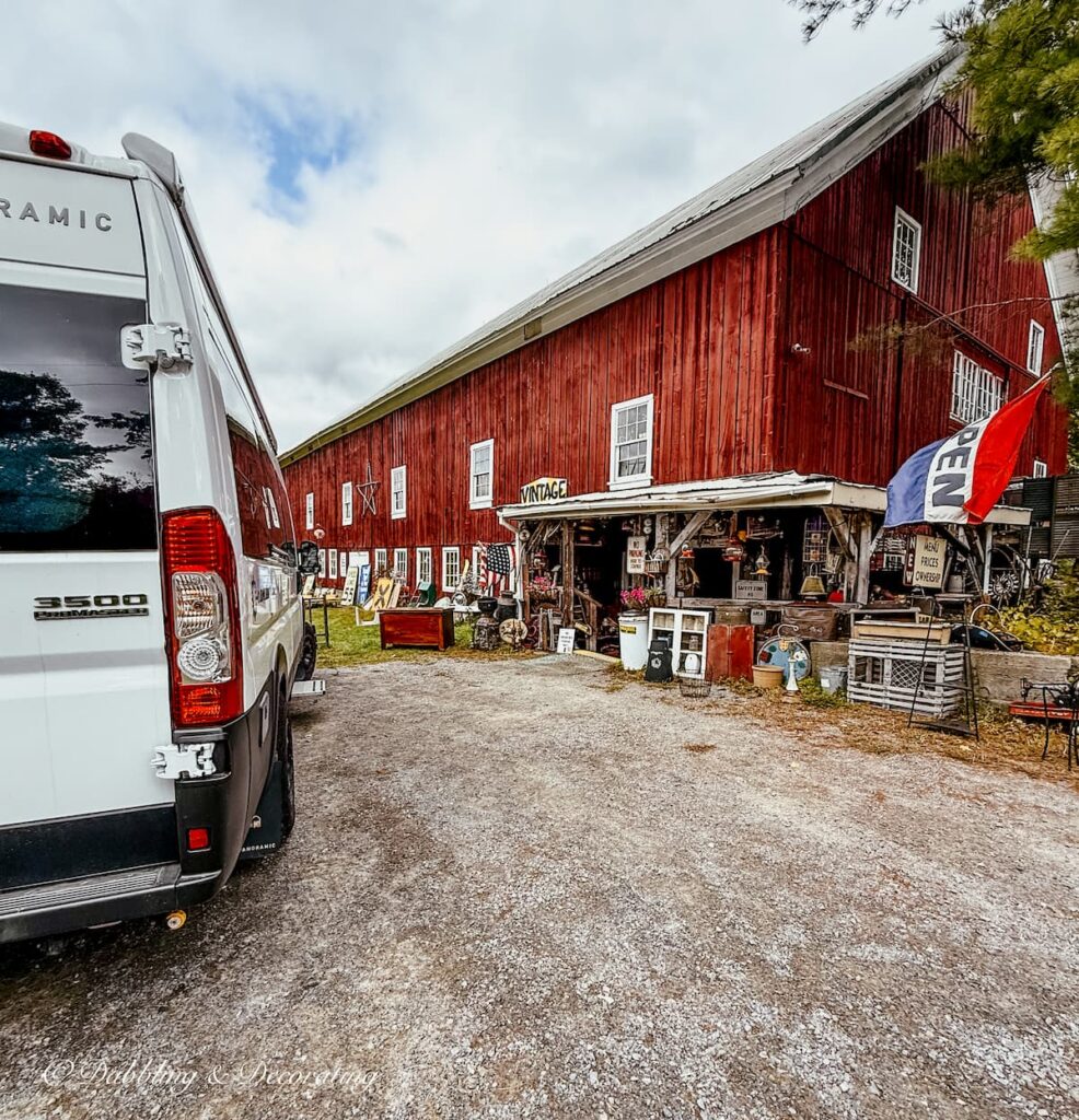 White RV in front of The Vintage Den Antiquing in Vermont at a Red Barn filled with eclectic antique finds.