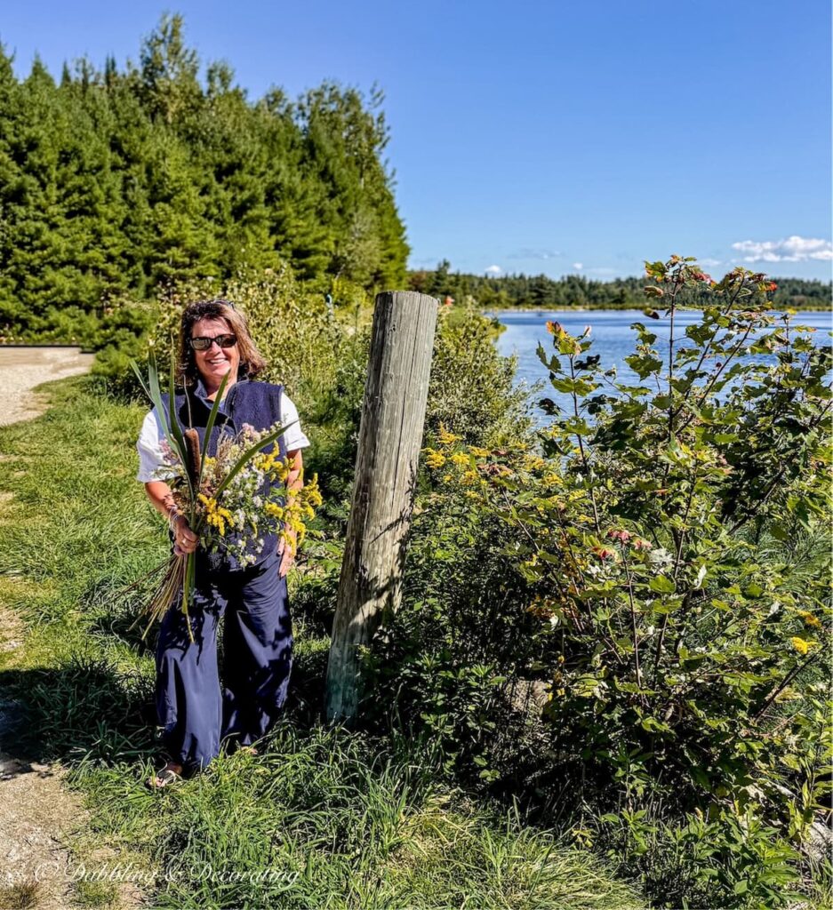 Ann, vintage home decor blogger with a Foraged Fall Arrangement in hand at Stratton Mountain Pond in Vermont.
