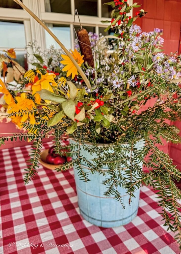 Vintage blue bucket filled with colorful foraged flower arrangement from walks around Vermont during early foliage season.