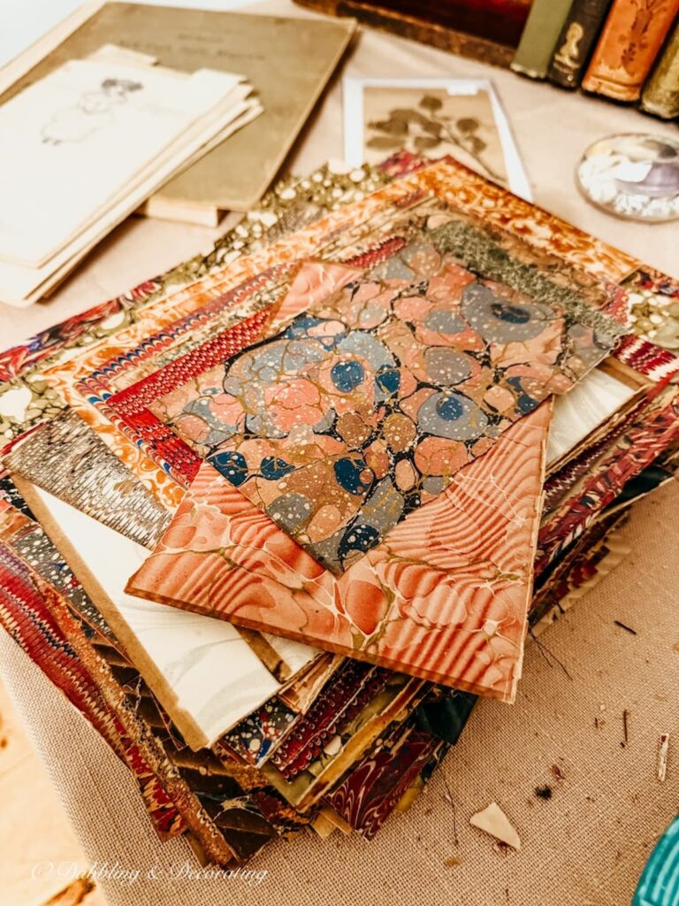 old marbled-paper book covers or cover boards in a pile inside an antique booth display.