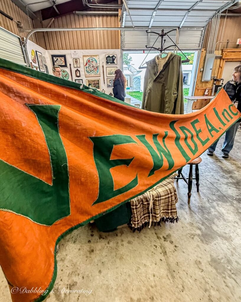 Large "New Ideas Lmtd" orange and green banner stretched out at The Taconic Antiques Fair.